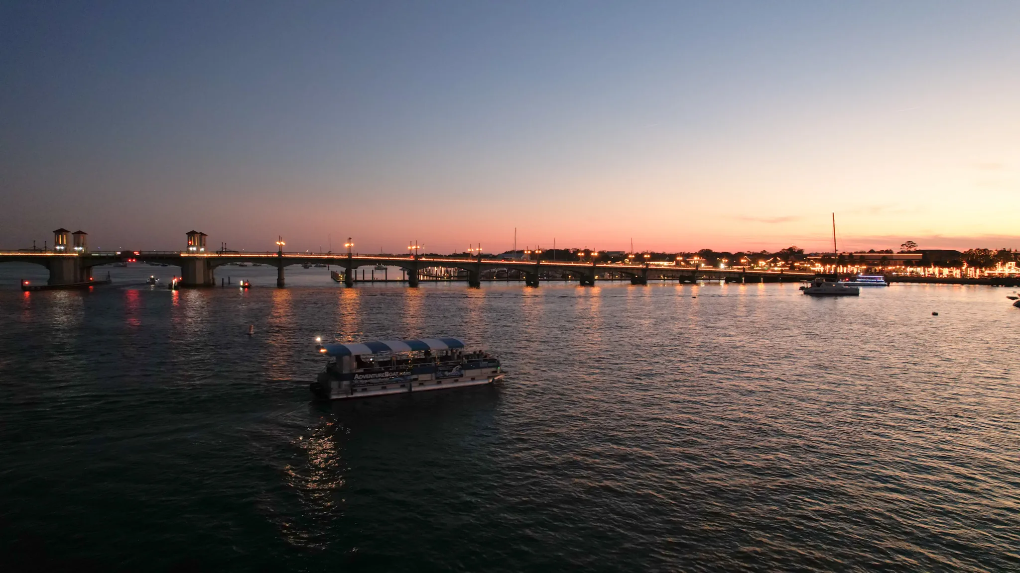 Adventure Boat Tours pontoon cruise near the Bridge of Lions at sunset in St. Augustine, Florida