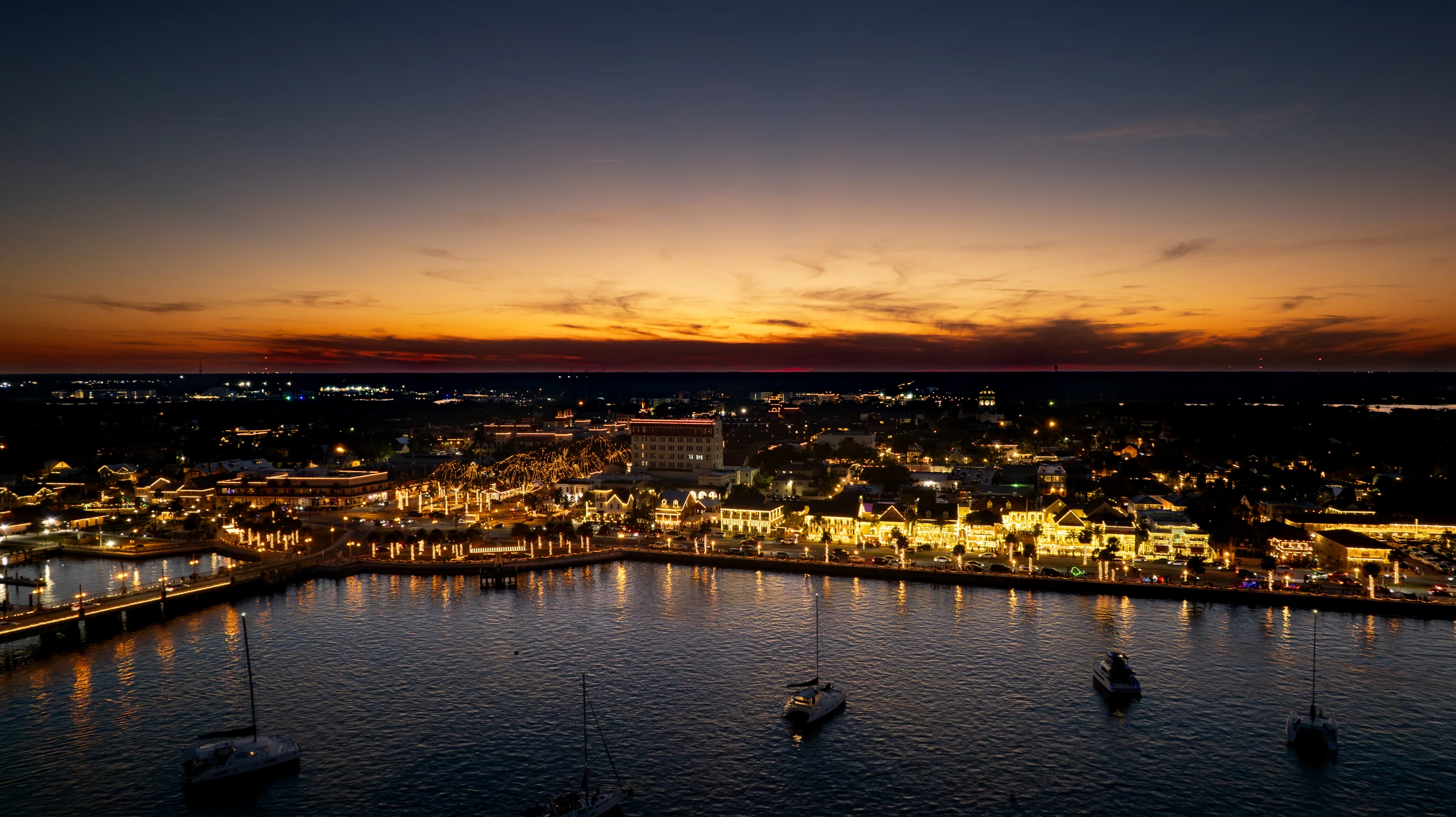 Aerial view of St. Augustine's illuminated waterfront at sunset during Nights of Lights