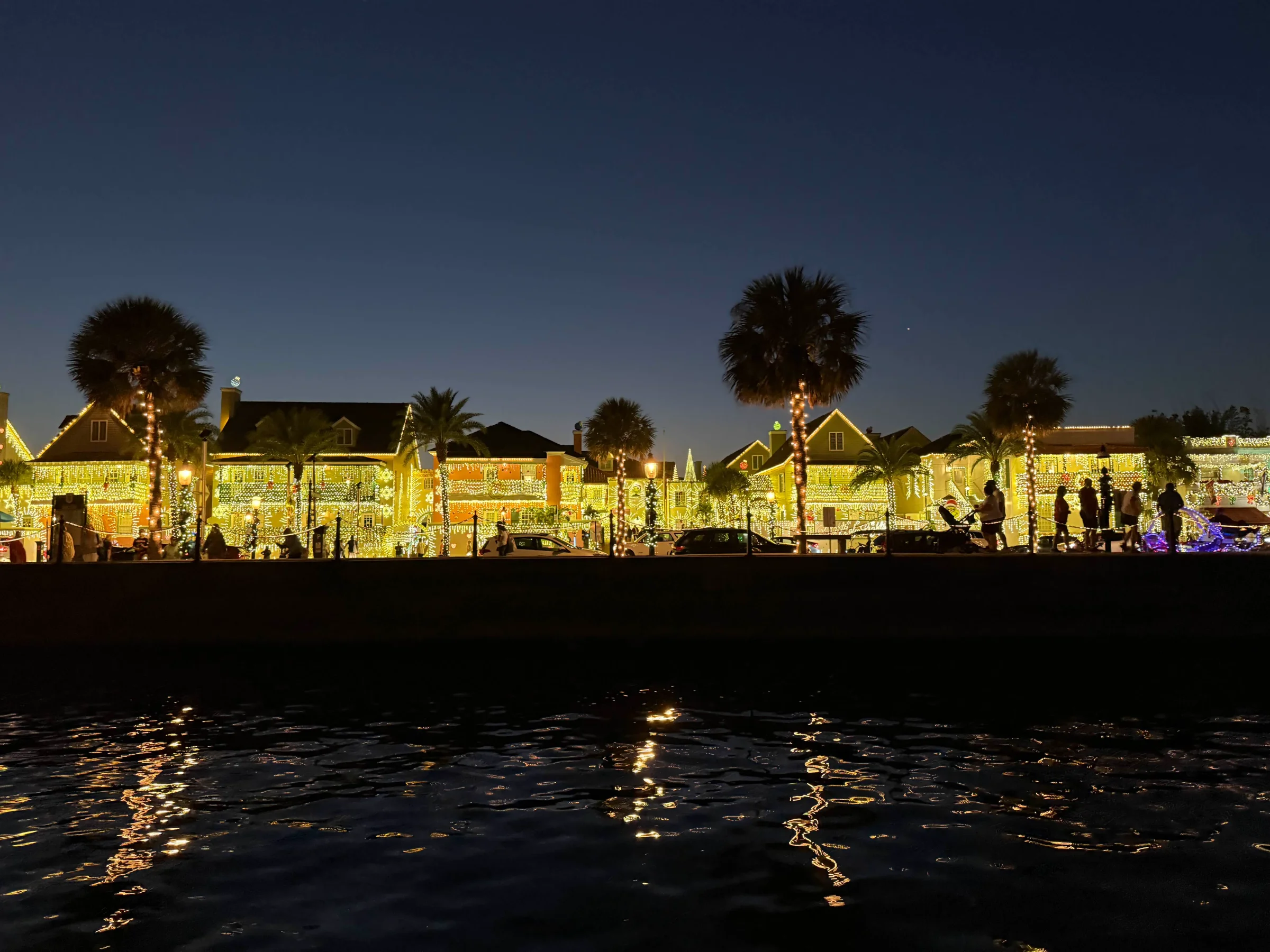St. Augustine waterfront buildings and palm trees covered in Nights of Lights, viewed from the water at night